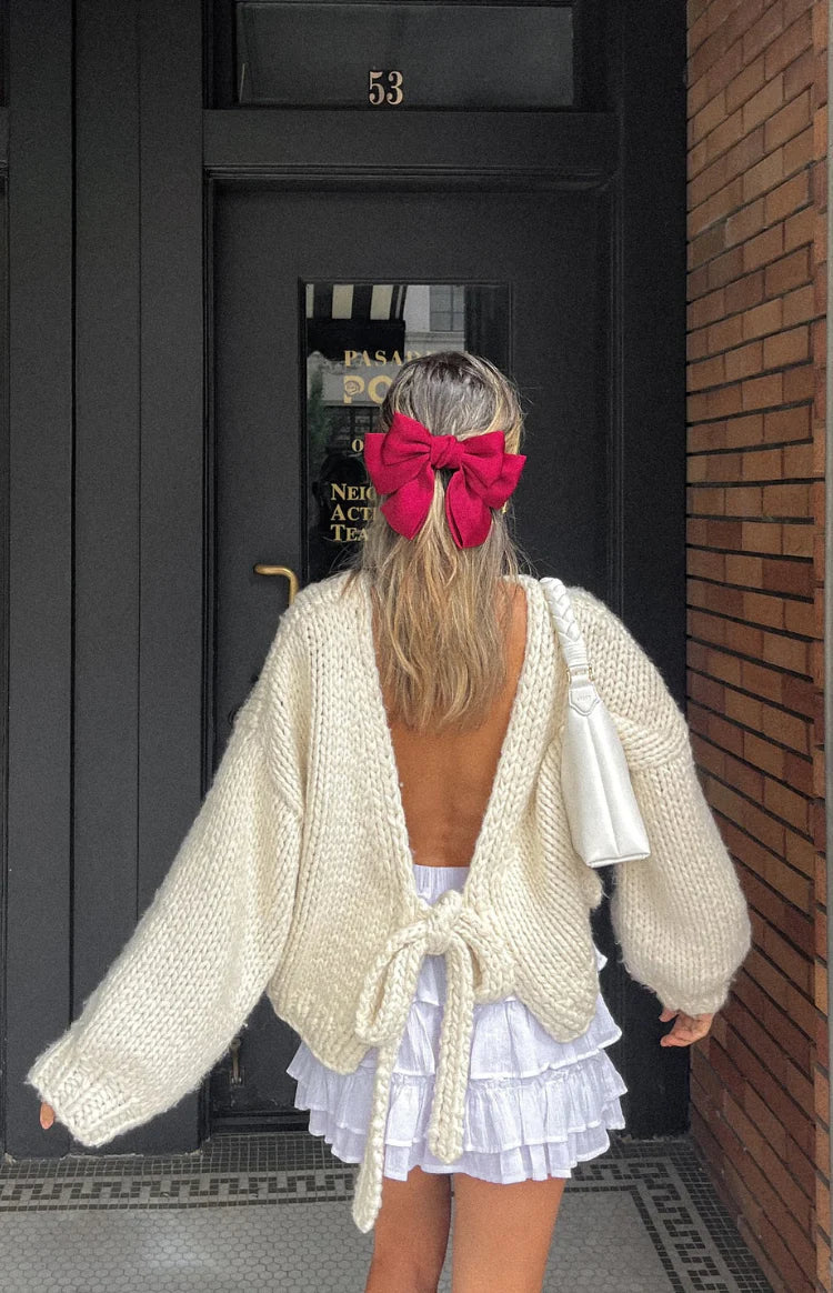 Rear view of a cream chunky knit cardigan with voluminous sleeves and a cropped hem