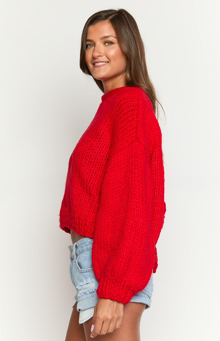 Side view of a red chunky knit cardigan with oversized balloon sleeves