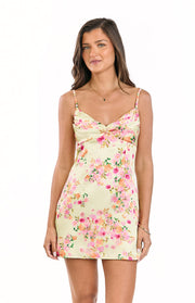 Front view of a honey yellow mini dress with a pink floral print, featuring a ruched and twisted bust detail and thin spaghetti straps
