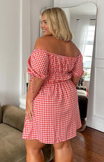 Rear view of a red gingham mini dress with an off-shoulder neckline, shirred waist, and puff sleeves with ties