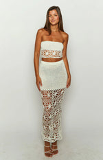 Side view of a white crochet maxi skirt with a fitted silhouette and openwork floral pattern at the hem