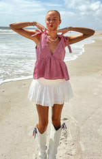 White broderie mini skirt with a tiered, flared silhouette and scalloped hem