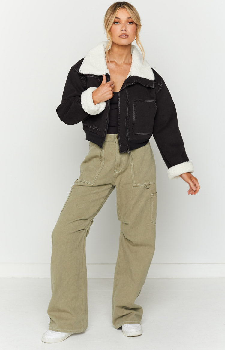 Close-up of a black denim sherpa jacket with white sherpa collar and cuffs, featuring white contrast stitching and silver zip