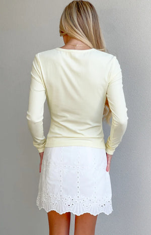 Rear view of a yellow ribbed knit long sleeve top with a round back neckline and fitted silhouette