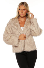 Side view of a sand faux fur jacket with a wide collar and plush texture
