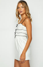 Side view of the white mini dress showing the smocked bodice with black trim and small black bows
