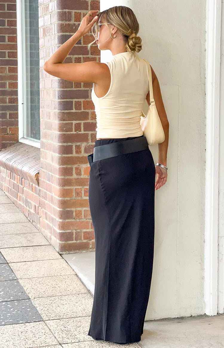 Side view of a black maxi skirt with a wide flat waistband and a flowing silhouette