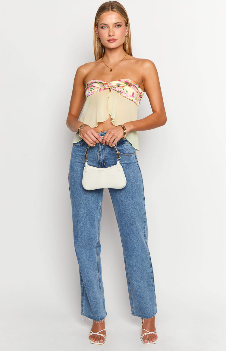 Front view of a yellow strapless top with a floral bust band, twisted front detail, and a flowy asymmetrical hem