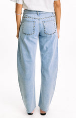 Rear view of light wash low rise jeans with silver studs along the waistband and outlining the back pockets