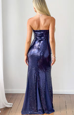 Rear view of a navy sequin strapless maxi dress with a back zipper and a flared hem revealing plain navy fabric