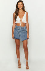 Washed blue denim mini skirt with an asymmetrical wrap-style front and raw frayed hem