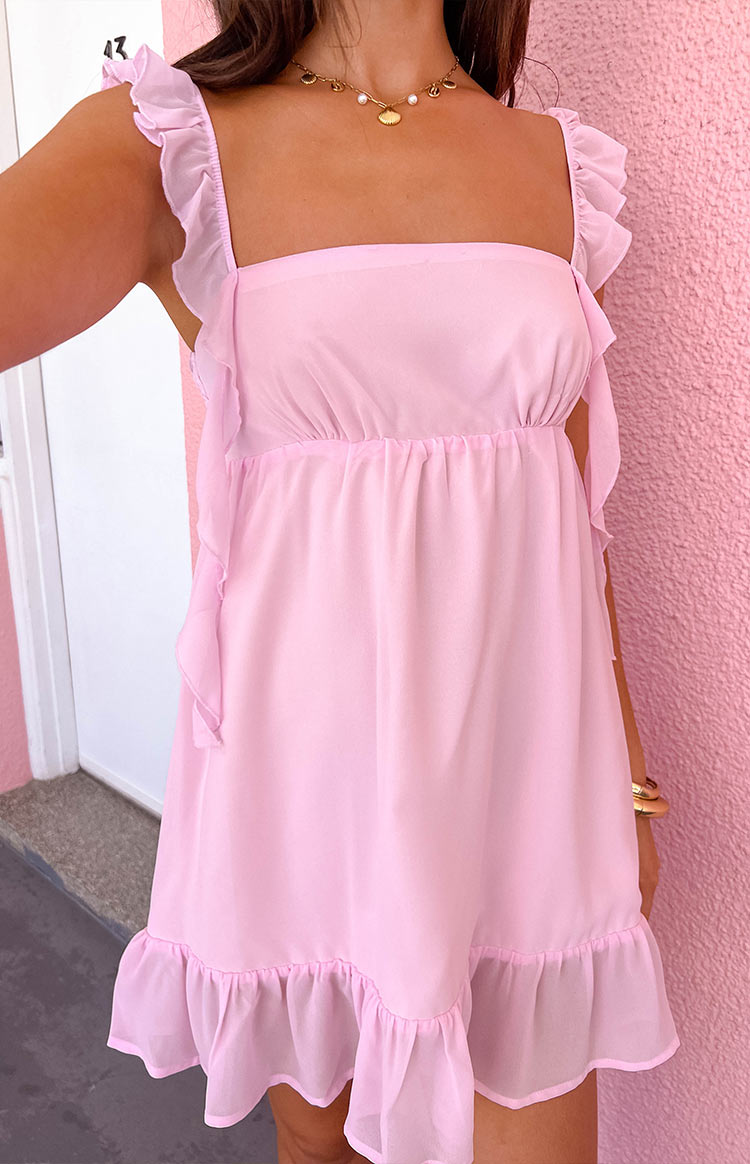 Detail shot of the light pink mini dress showing ruffled shoulder straps, side ties, and gathered empire waist
