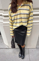 Black PU midi skirt with a fitted pencil silhouette and subtle ruching detail on the hip