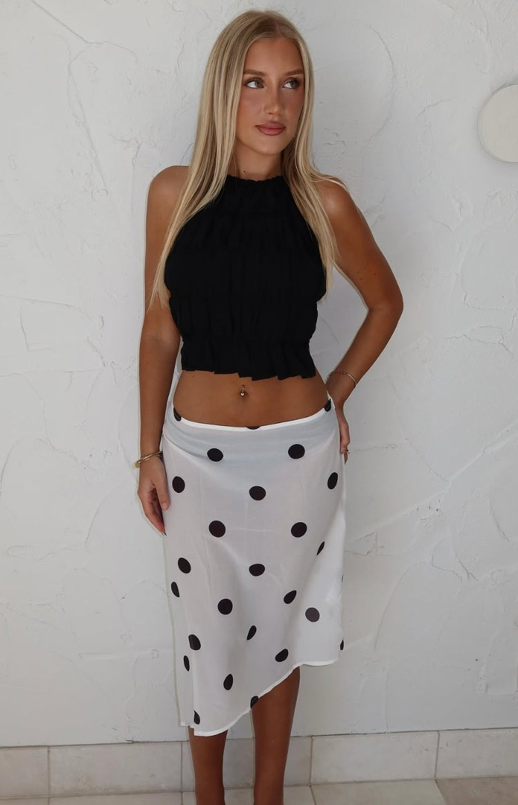 Front view of a white sheer midi skirt with black polka dots, featuring a flowy fit and an asymmetrical hemline