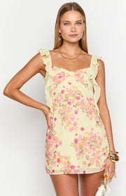 Front view of the yellow chiffon mini dress showing the pink floral print, ruffled straps, and bow bust detail