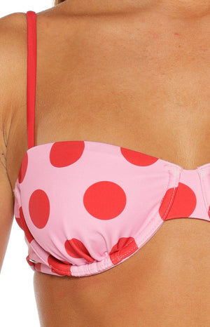 Close-up of the pink bikini top with red polka dots, showing the thin red shoulder strap and ruched cup edge