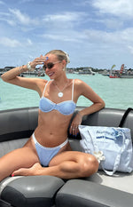 Blue gingham underwire bikini top with white lace trim and matching high-cut bottoms on a boat