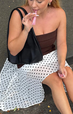 Side view of a white polka dot hanky hem midi skirt with a flowy silhouette