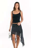 A white ribbed halter neck tank top paired with a black midi skirt featuring white polka dots and a stylish handkerchief hem- ideal for a breezy casual outfit.
