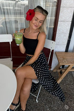 Front view of a black polka dot midi skirt with a flowy hanky hem and irregular points