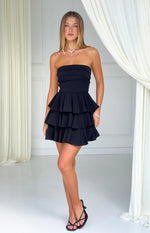 Black strapless mini dress with a fitted bodice featuring horizontal pleats and a three-tiered ruffle skirt