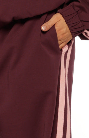 Close up of burgundy wide leg track pants with light pink side stripes comfortable for lounging or travel