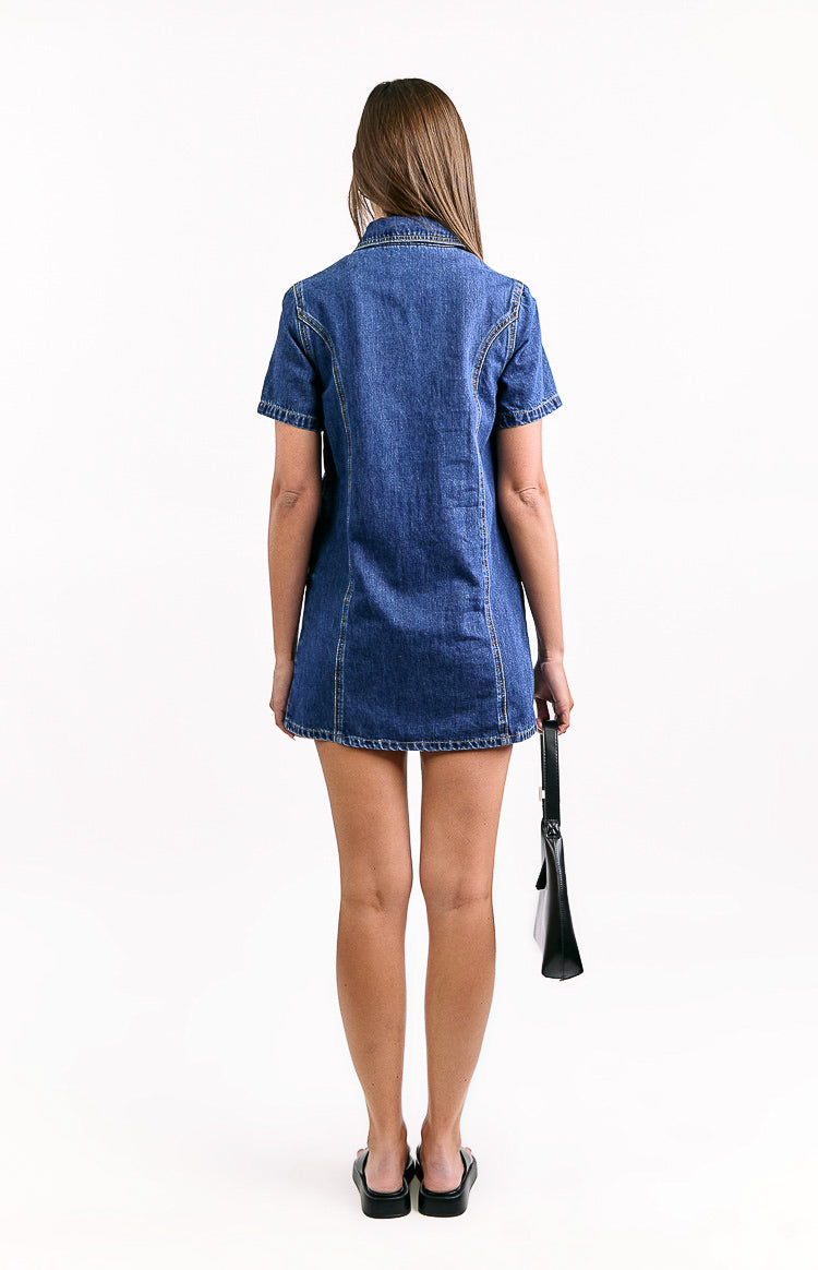 Rear view of a dark wash denim mini dress with a collar, short sleeves, and vertical seam detailing