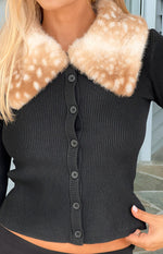 Close-up of the black ribbed knit cardigan with a spotted faux fur collar and button-front detail