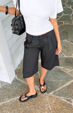 Black tailored culottes with front pleats, a structured waist, and a wide knee-length cut