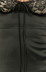 Close-up of the black lace bust with beige lining and a central drawstring tie, above the smooth black satin fabric