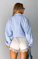 Front view of a blue stripe funnel neck jacket with braided stitch detail and voluminous gathered sleeves