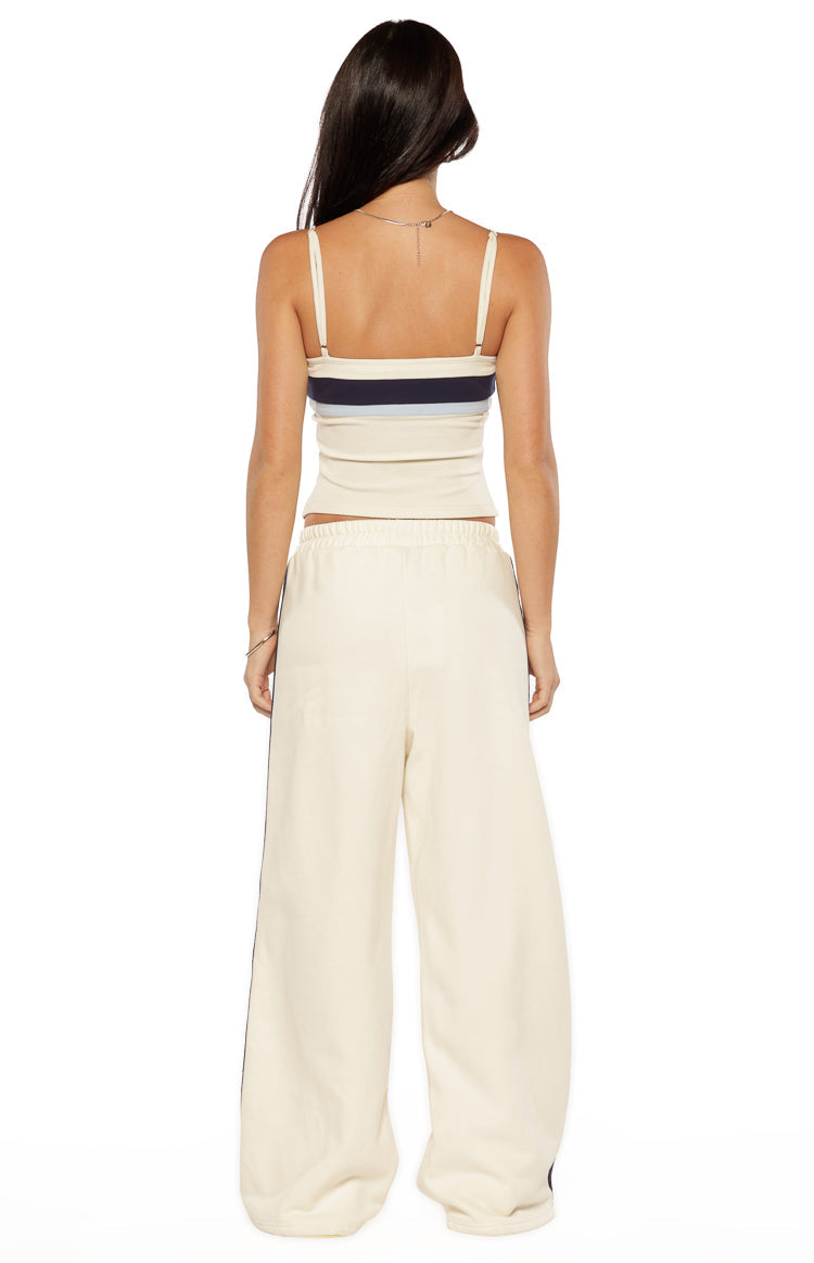 Rear view of a white singlet with thin spaghetti straps and navy and light blue horizontal stripes across the upper back
