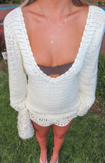 White crochet mini dress with a deep scalloped V-neckline, long sleeves, and a scalloped mini hem