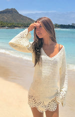 White crochet mini dress with a V-neck, long bell sleeves, and a scalloped hem with circular motifs, beach