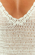 Close-up of the white crochet mini dress showing the scalloped V-neckline and open knit fabric