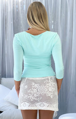 Rear view of a white crochet lace mini skirt with intricate floral patterns and a scalloped hem