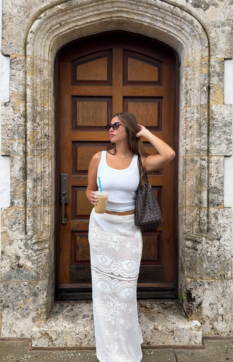 Full length white crochet lace maxi skirt with a fitted silhouette and intricate sheer floral patterns