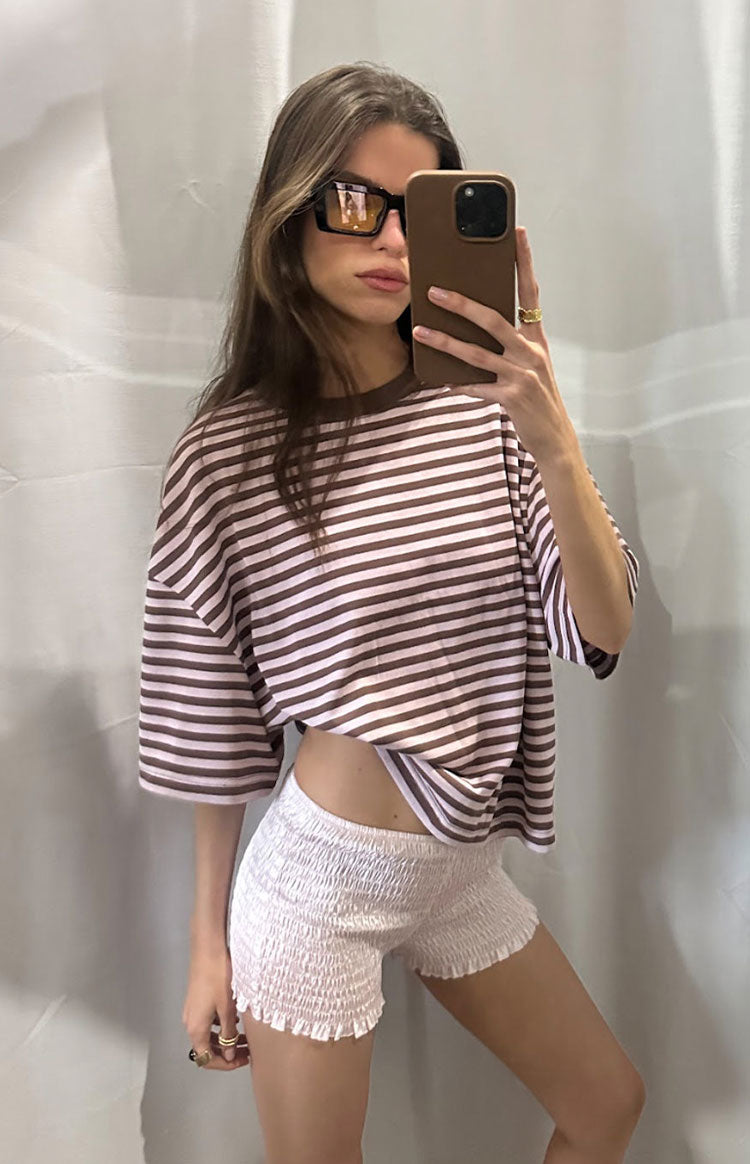 Woman in a brown and pink striped oversized cropped tee with white shorts a sweet and casual look for Spring