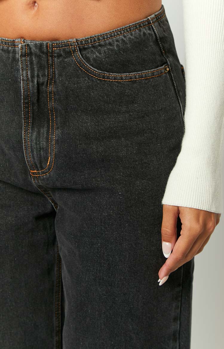 Front close-up of charcoal denim jeans with curved front pocket, fly, and orange contrast stitching