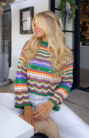 Open knit multi-coloured sweater with chevron stripes, a round neck, and long bell sleeves with ruffled cuffs