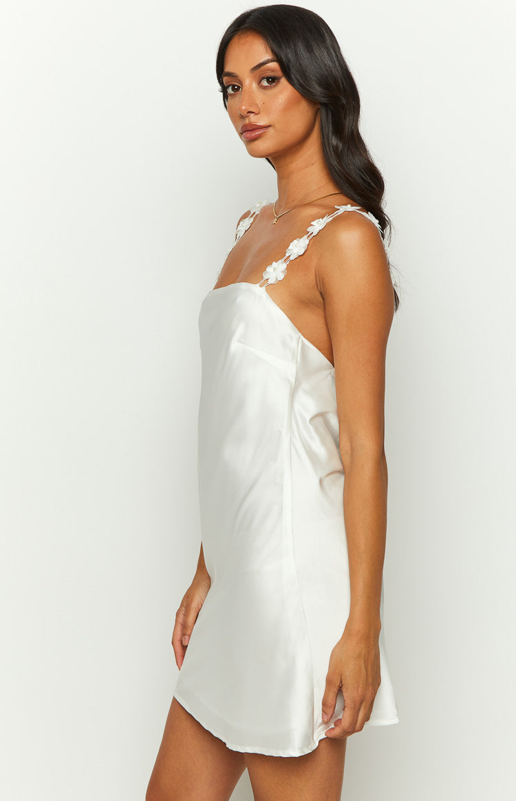 Side view of a white satin mini dress with square neckline and floral applique spaghetti straps
