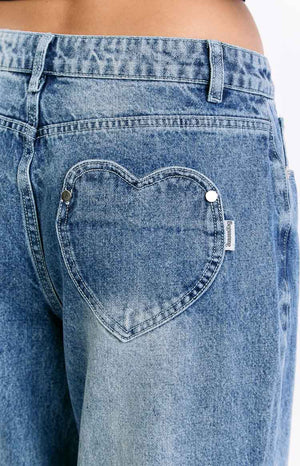 Rear view of mid wash denim slouchy jeans with unique heart-shaped back pockets and a relaxed wide-leg fit