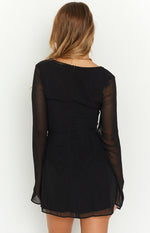 Rear view of a black long sleeve mini dress with a square back, sheer sleeves, center back zipper, and ruched detail