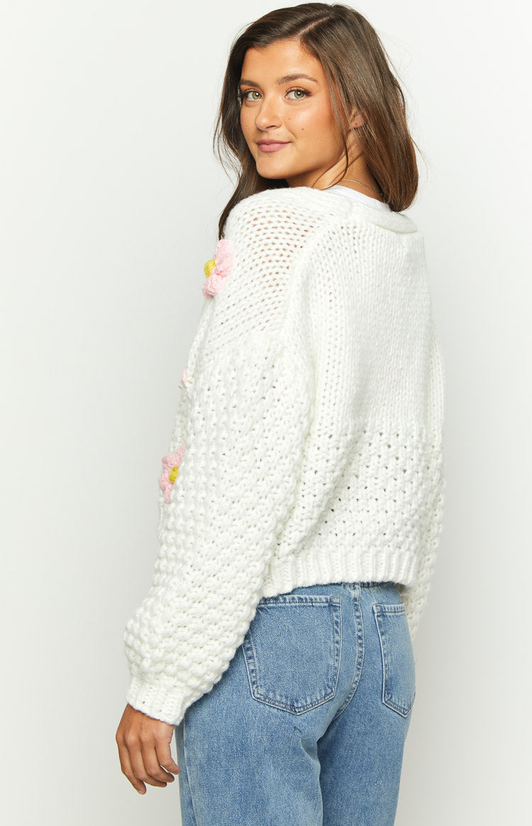 Close-up of the chunky white knit cardigan with pink flower appliques and yellow centers