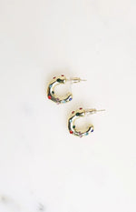 Flat lay of two gold mini hoop earrings with scattered red, green, blue, and pink stones and stud backs