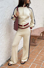 Cream knit wide-leg track pants with dark blue side stripes and ribbed red and cream waistband