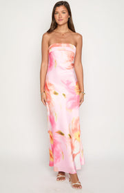 Front view of a pink strapless maxi dress with a straight neckline and a vibrant abstract floral print in orange, yellow, and green