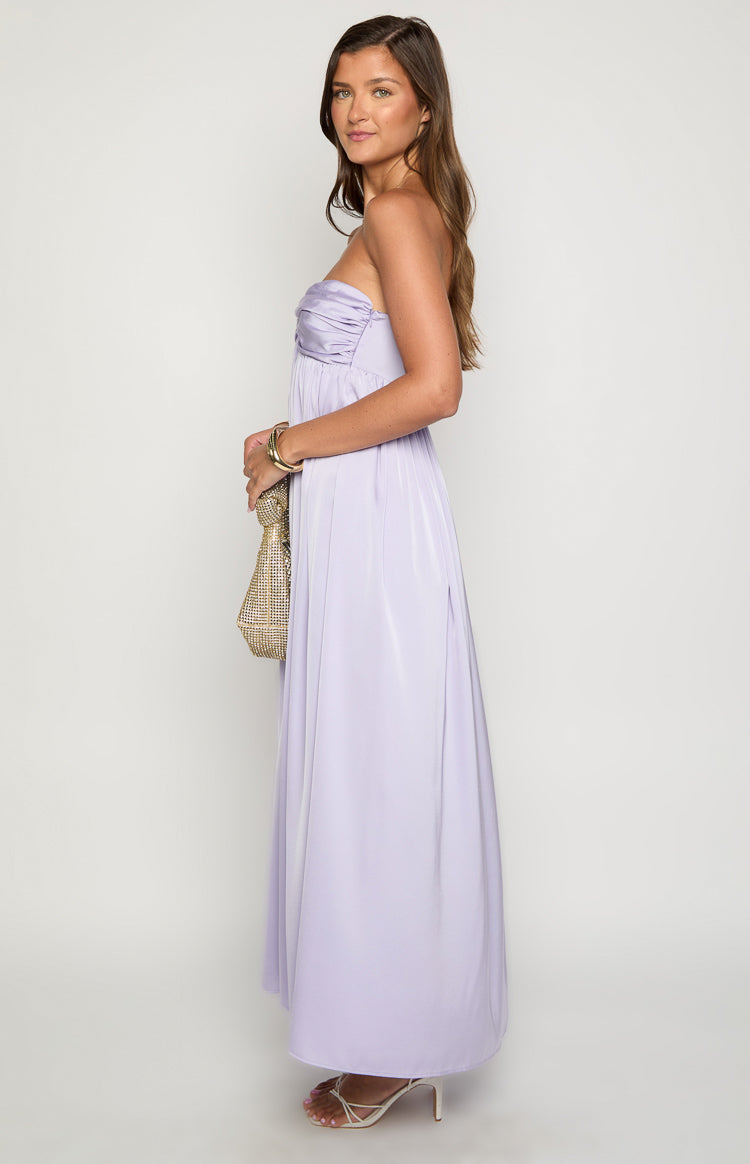 Side view of a lilac strapless maxi dress with a ruched bust and flowy full-length skirt