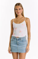 A close-up of a white spaghetti strap top adorned with pink and yellow beaded hibiscus flowers- paired with a light wash denim mini skirt.