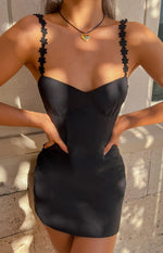 Close-up of the black mini dress with sweetheart neckline and delicate flower-shaped shoulder straps